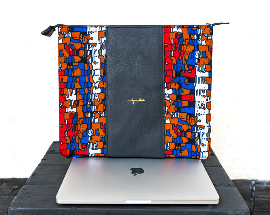 A multicolored laptop bag with a geometric pattern and a solid black panel, featuring a laptop partially inserted into it, displayed on a dark surface.