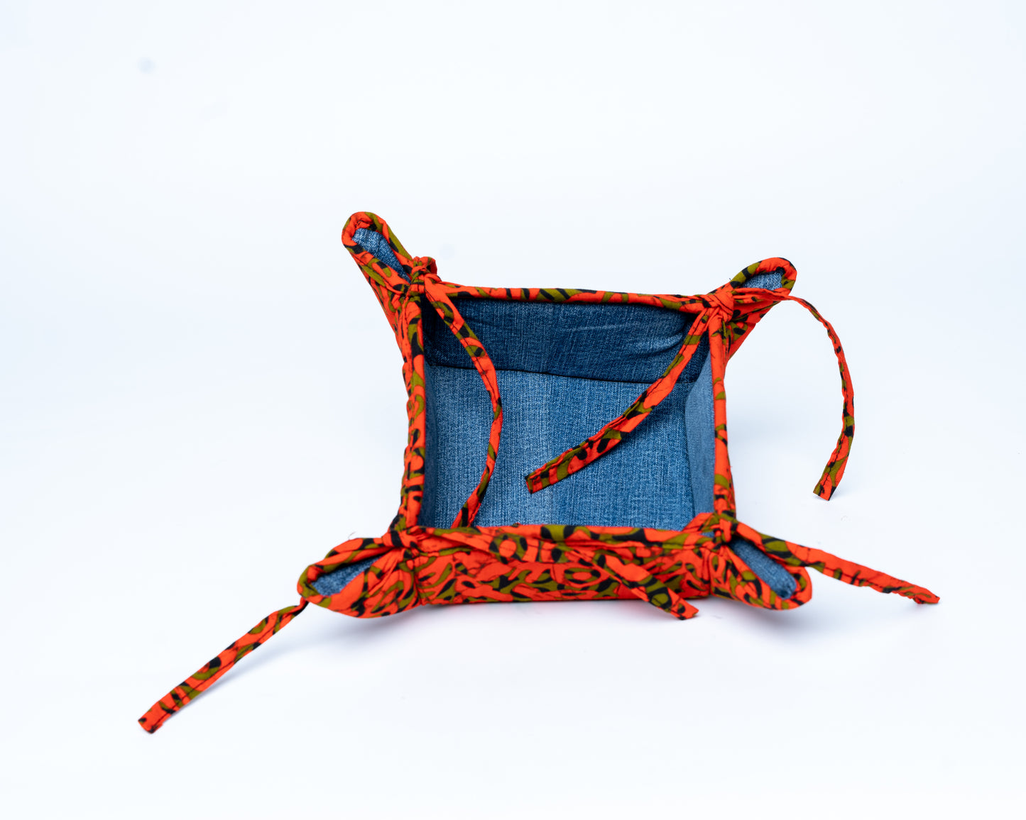 Small fabric basket with orange and black pattern on a white background