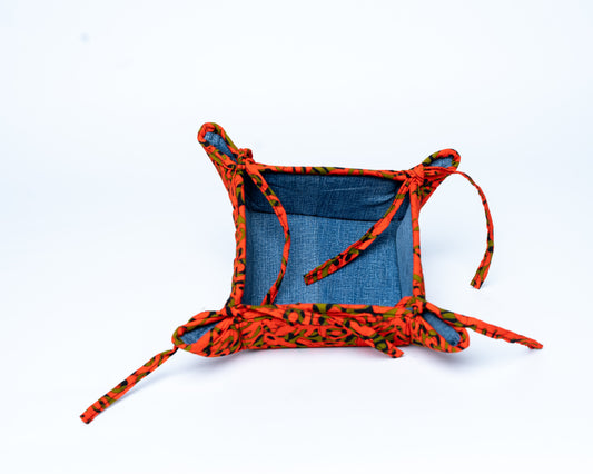 Small fabric basket with orange and black pattern on a white background