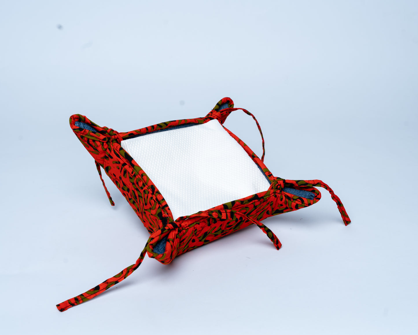 Red and black patterned pouch with a mirror on a light blue background