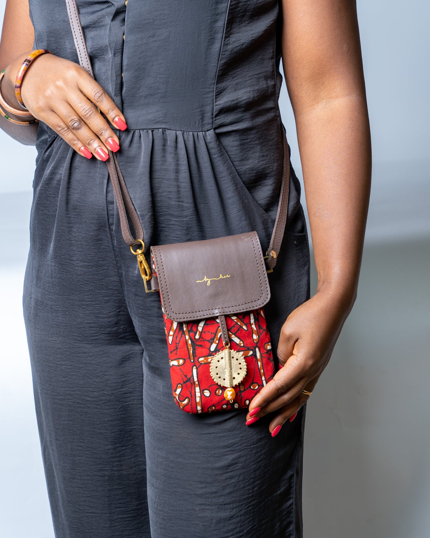 Person wearing a gray dress with a red patterned handbag
