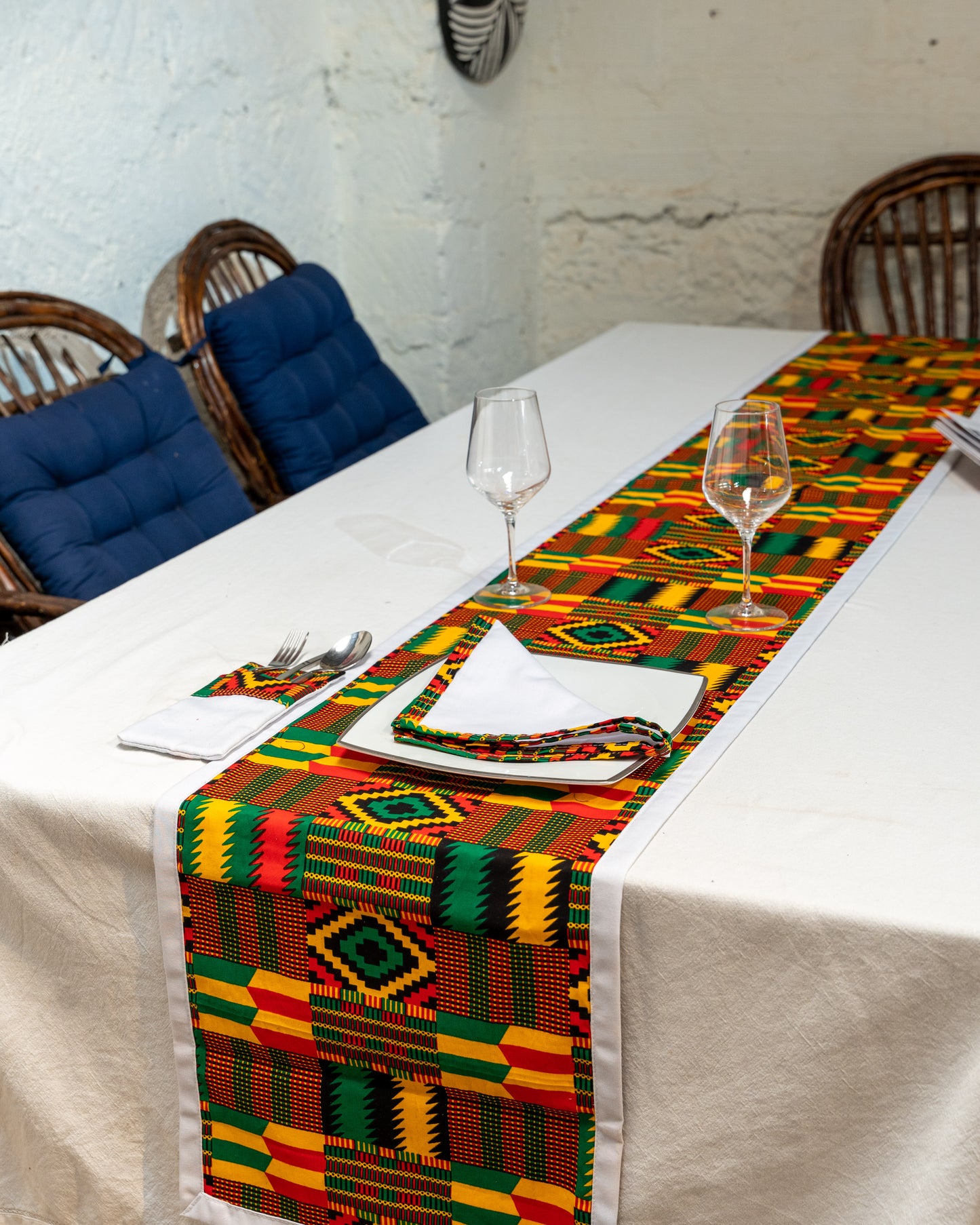 Table setting with a colorful geometric patterned table runner on a white tablecloth.