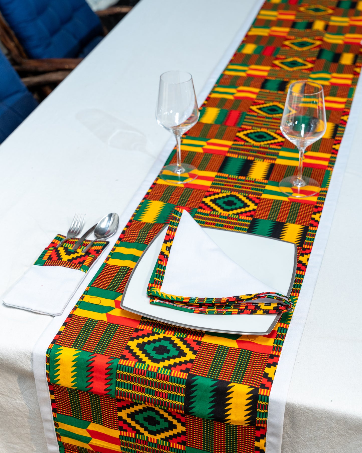 Colorful geometric patterned table runner on a white table with cutlery and glasses.