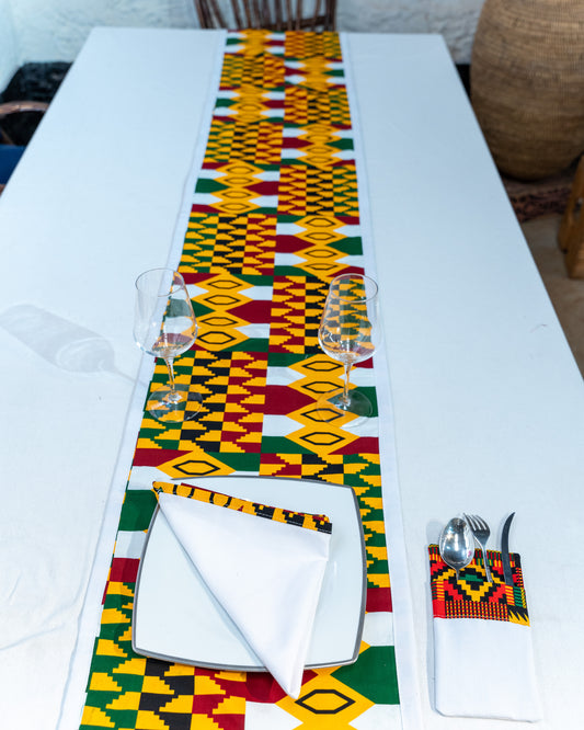 Dining table set with a colorful patterned table runner, plates, and cutlery.