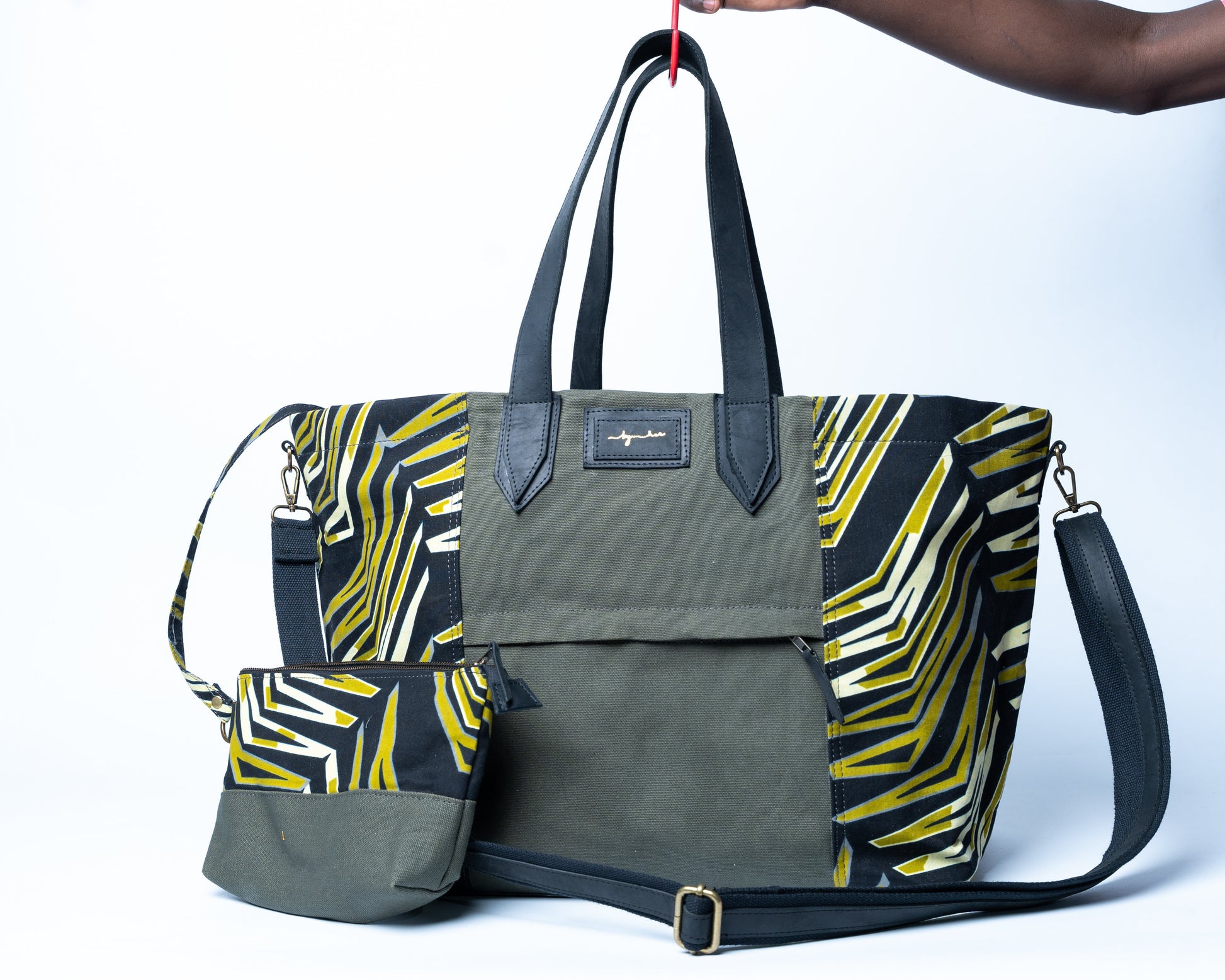 Green and yellow patterned bag with a matching pouch held by a person against a white background