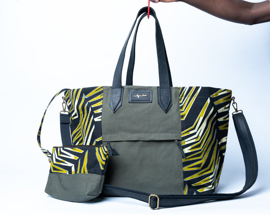 Green and yellow patterned bag with a matching pouch held by a person against a white background