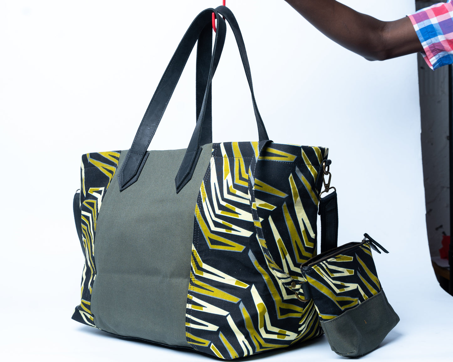 Gray tote bag with geometric pattern held by a person against a white background