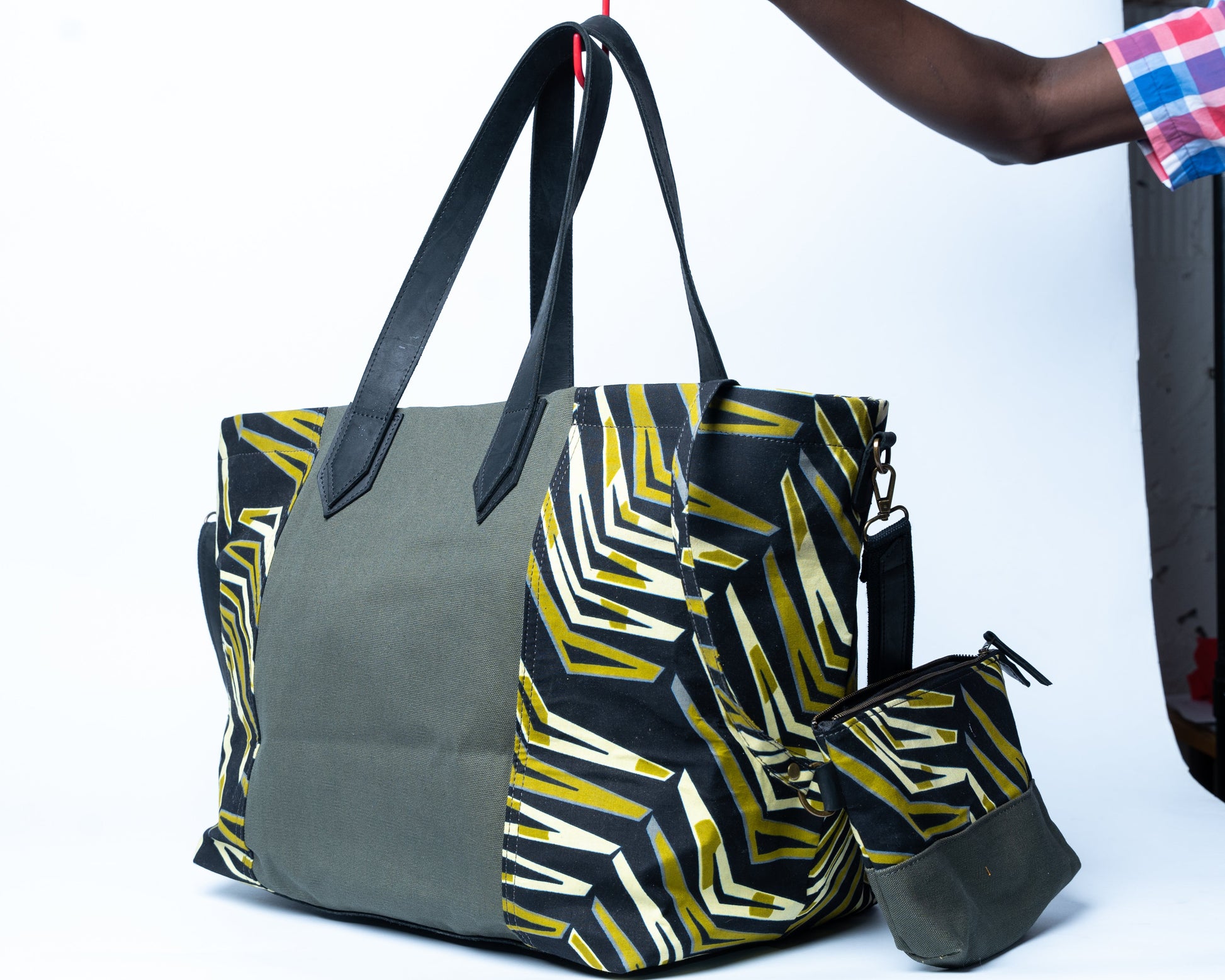 Gray tote bag with geometric pattern held by a person against a white background