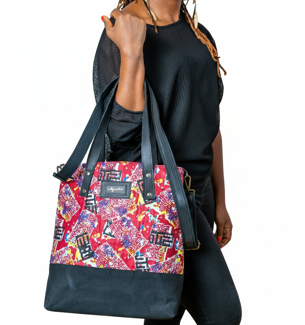 Woman holding a colorful patterned bag against a white brick wall.
